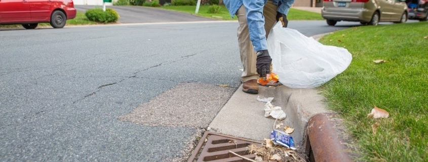 Man picking up debris from street storm drain