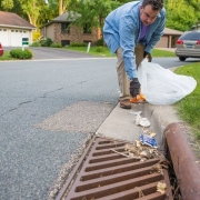 man picking up trash from storm drain
