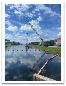 Crane lifting equipment into canal for construction of water control structure