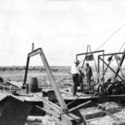 old photo from 1919 of dredge and car driving by