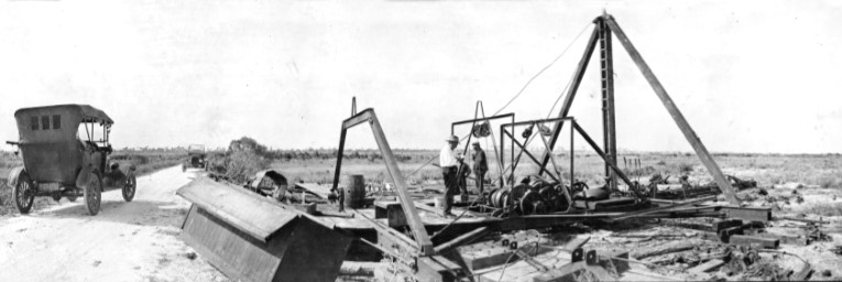 old photo from 1919 of dredge and car driving by